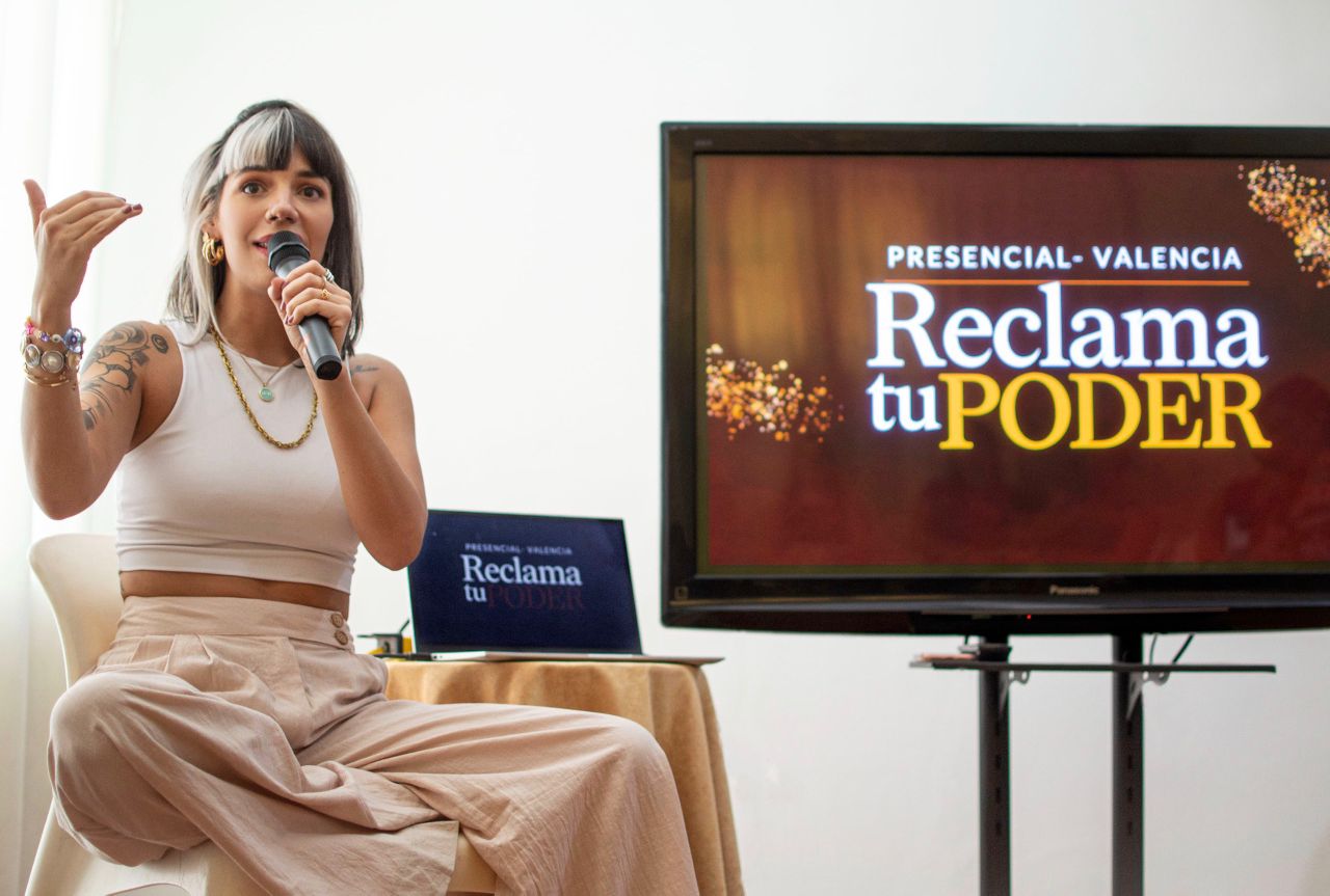 Graziella Sevilla impartiendo un encuentro presencial con micrófono.
